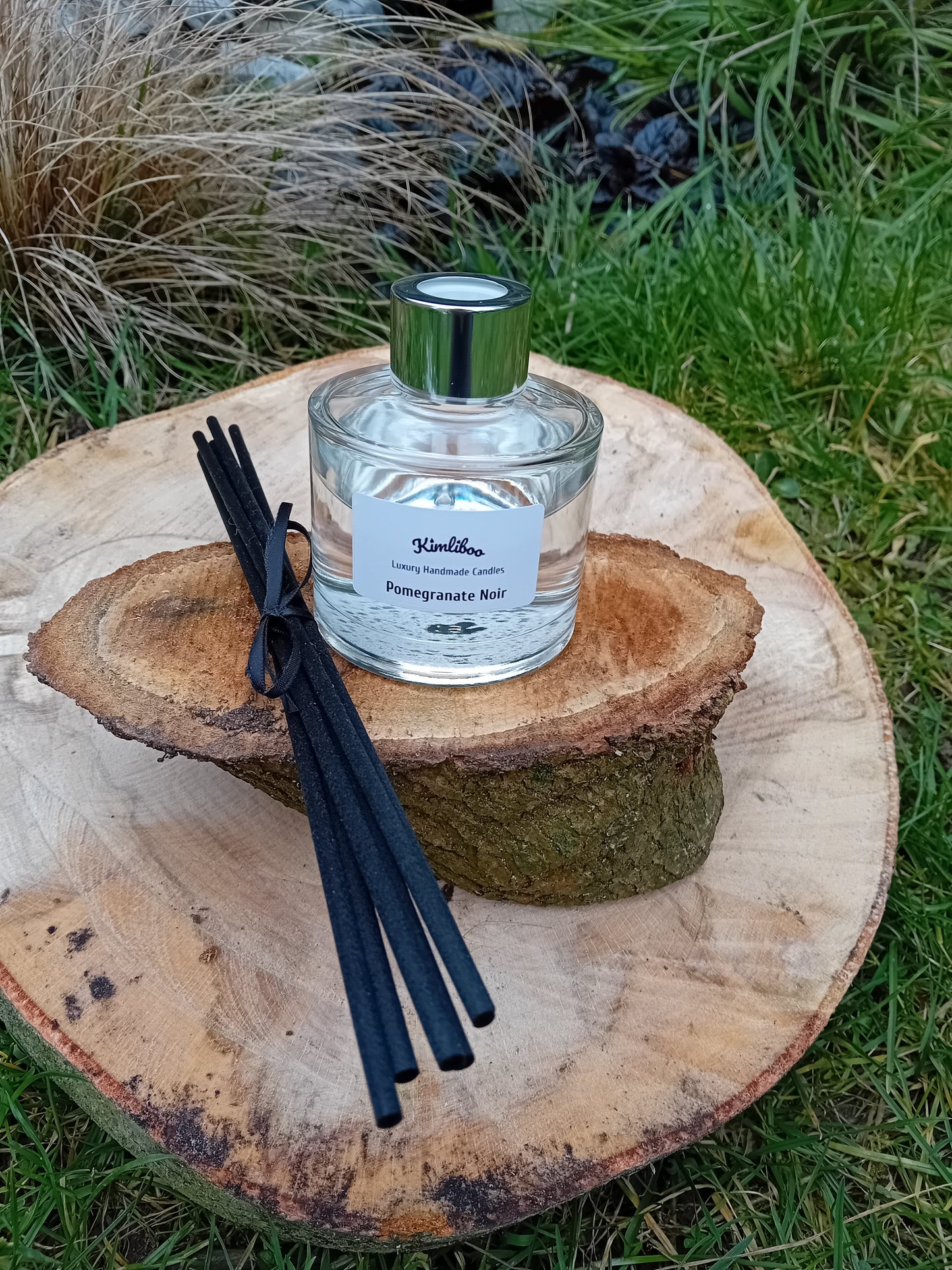 Pomegranate Noir fragranced reed diffuser with a 100ml clear glass jar and a bundle of black fibre reeds.