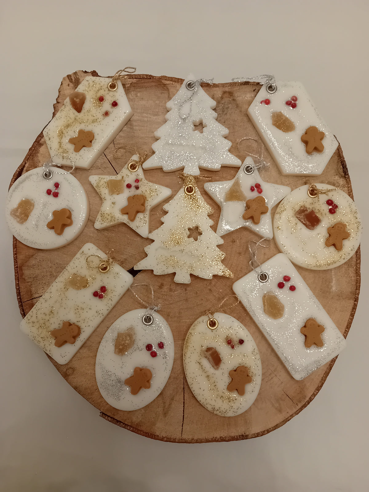 Wooden log slice with variously decorated shaped wax sachets on a log slice background.